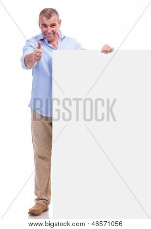 lässig senior Man hält eine leere Pannel und zeigen die Daumen hoch Geste, um die Kamera mit einer smil