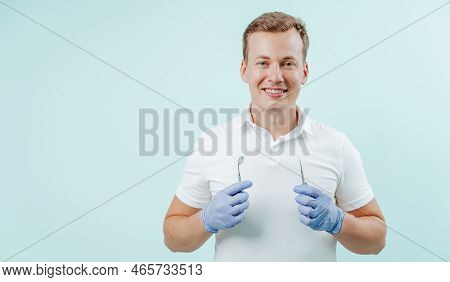 Doctor Dentist Smilling And Holding Dental Instrumentation In His Hands On Light Blue Background. Sm