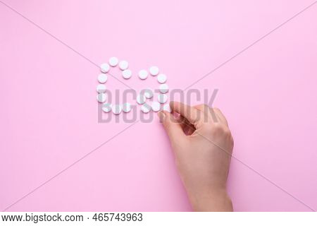 Woman Making Calcium Symbol With White Pills On Pink Background, Top View