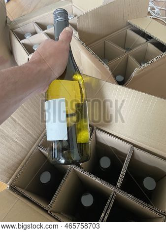 A Person Is Un Packing A Bottle Of Wine Ordered On The Internet Out Of A Delivery Box