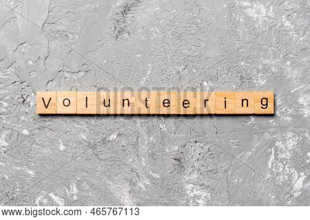 Volunteering Word Written On Wood Block. Volunteering Text On Table, Concept.