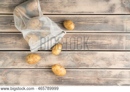 Composition Of Raw Fresh Potato In Transparent Packet On Wooden Background. Degradable Package, Zero
