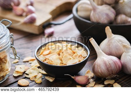 Bowl Of Dried Garlic Flakes. Heads Of Garlic, Glass Jar Of Garlic Flakes On Kitchen Table. Dried Sea