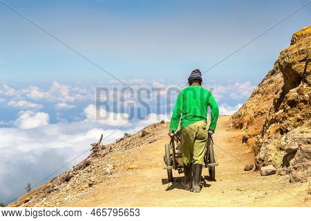 Miner Extracting Sulfur Inside The Crater Of Active Volcano Ijen, Java Island, Indonesia