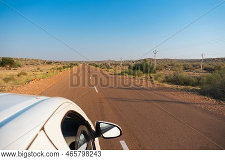 White Car Running Through Empty High Road Or National High Way Passing Through The Desert. Distant H