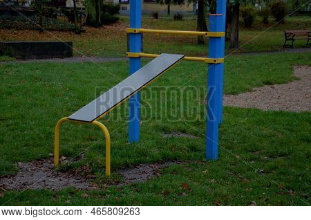 Outdoor Sports Field. Exercise Equipment With Gymnastic Rings To Strengthen The Arms. Bench For Trai