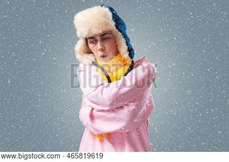 Freezed Young Woman In A Ushanka Hat And Yellow Scarf Is Breathing, Hugging Herself Trying To Keep W