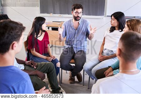 Diverse Group Of High School Students Sitting On Chairs In A Circle And Interacting During A Lesson,