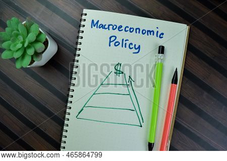 Concept Of Macroeconomic Policy Write On A Book Isolated On Wooden Table.