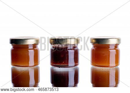 Jam In Many Jars On A White Isolated Background With Reflection. Orange Jelly Apricot Apple. Concept