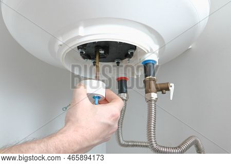 The Hand Of A Plumber Installs A Thermostat In A Boiler After Repair. Water Heater Repair.