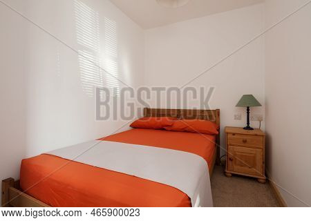 Toft, Cambridgeshire, England - March 4 2019: Compact Furnished Sunlit Bedroom In Orange And White W
