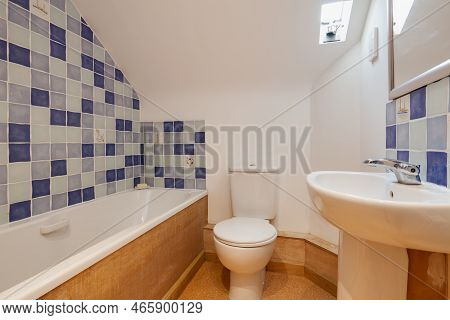 Toft, Cambridgeshire, England - March 4 2019: Basic Part Tiled Bathroom In Blue And White With Slopi