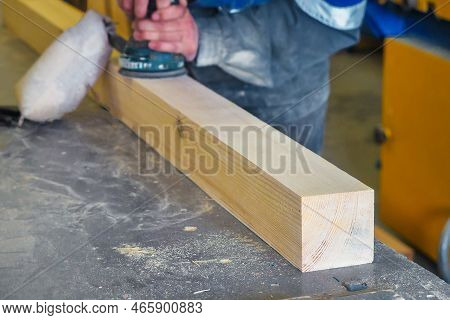 Professional Woodworker Grinds Wooden Bar On Workbench In Carpentry Workshop With Tool. Middle-aged