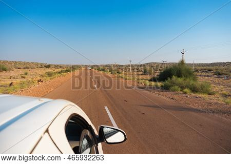 White Car Running Through Empty High Road Or National High Way Passing Through The Desert. Distant H