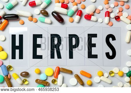 Word Herpes Surrounded By Different Pills On White Background, Top View