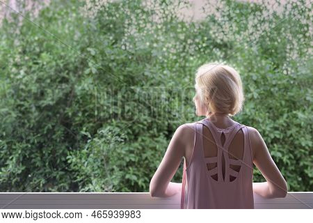 A Woman At The Open Panoramic Slider Window Looks At The Lush Greenery In Front Of Her Windo
