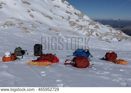 Climbing Equipment - Colored Backpacks, Ropes, Helmets Lie On A Snowy Slope, Austria, Alps, Dachstei