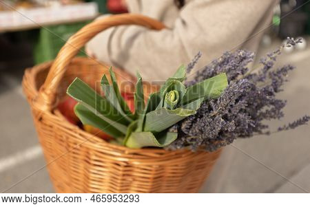 A Woman Holds A Wicker Basket With Apples, Onions And Lavender In Her Hands. Shopping Market, Austri