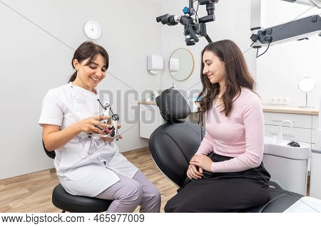 Dentist Holding Dental Articulator With Dental Gypsum Prosthesis Model Showing It To A Patient