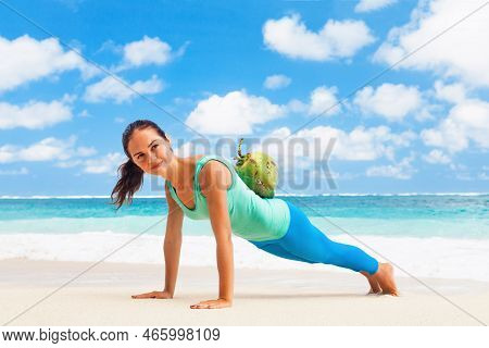 At Sea Beach Active Woman Doing Fitness Exercises Plank, Push Up With Coconut On Back To Keep Fit. B