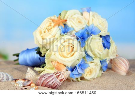 Beautiful wedding bouquet with roses on sand, on nature background