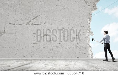 Young determined businessman with hammer in hands