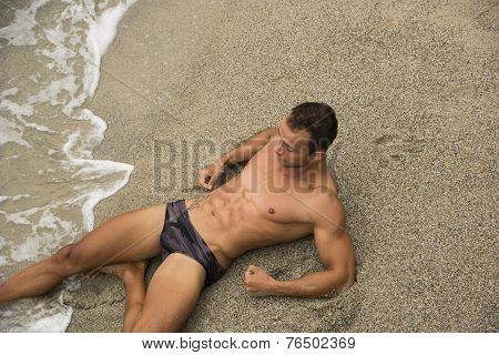 Attractive Shirtless Muscleman In Swimming Suit Lying On The Beach