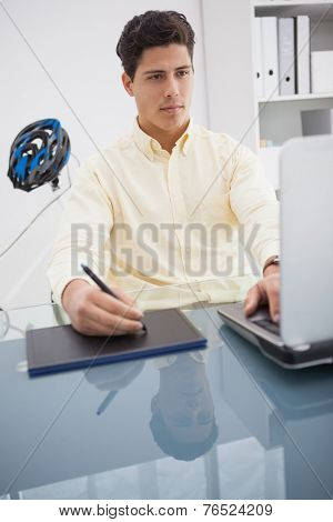 Concentrated designer using laptop and degitizer in his office