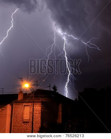 lightning falling behind a house
