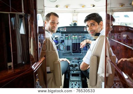 Portrait of confident pilots in corporate plane cockpit