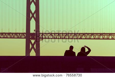silhouette couple sitting together with bridge in pastel, vintage style