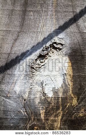 A wooden background with a white stain and a shadow of a rope