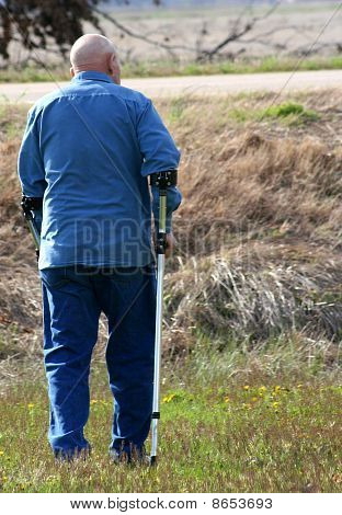 Muž chůzi s berlemi ve venkovském prostředí