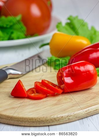 Sliced Red Paprika On The Wooden Board With Colorful Vegetables On Background