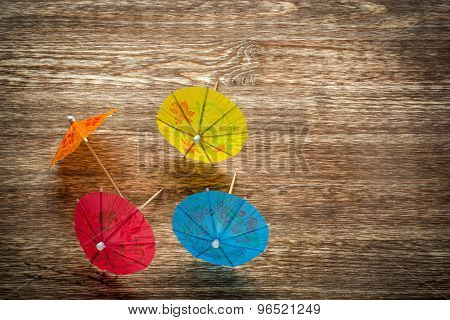 Colourful cocktail umbrellas lying on a wooden backdround, conceptual for partying and festivity