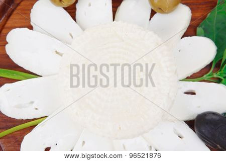 dairy products : feta white cheese sliced on cut board with olives and basil leaves isolated over white background