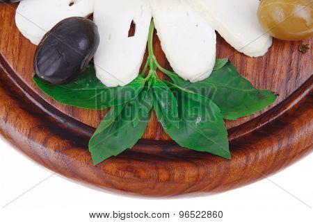 dairy products : feta white cheese sliced on cut board with olives and basil leaves isolated over white background