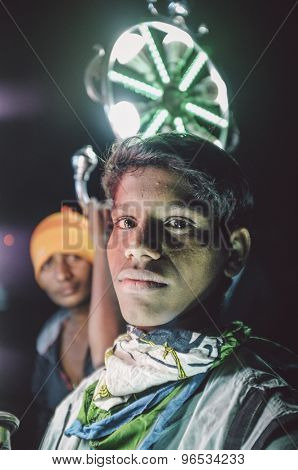 JODHPUR, INDIA - 08 FEBRUARY 2015: Young Indian boys work as light holders in bride-grooms wedding procession. Post-processed with grain, texture and colour effect.