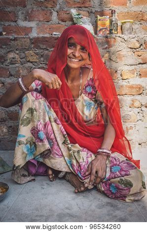 GODWAR REGION, INDIA - 13 FEBRUARY 2015: Indian woman in sari sits next to brick wall. Post-processed with grain, texture and colour effect.