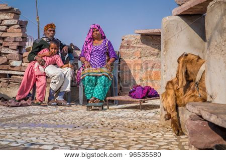 JODHPUR, INDIA - 09 FEBRUARY 2015: Grandparents rest with granddaughter on roof terrace of home with goat sitting close by.