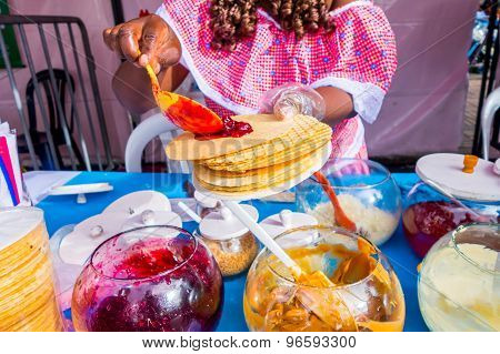 Closeup traditional Colombian streetsnack oblea being prepared adding white sauce with top of jam an