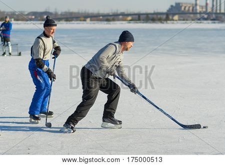 DNEPR UKRAINE - JANUARY 22, 2017: Mature amateur men playing hockey on a frozen river Dnepr in Dnepr city, Ukraine at January 22, 2017