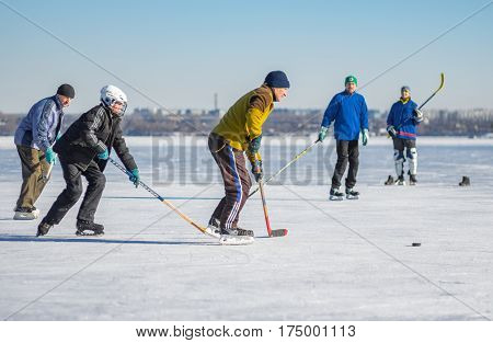 Dnepr Ukraine - January 22 2017: People of different ages playing hockey on a frozen river Dnepr in Dnepr city, Ukraine at January 22, 2017