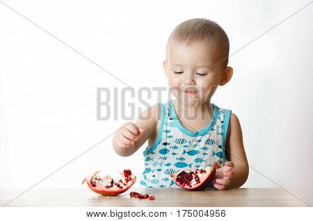 Baby eats a pomegranate ripe and juicy very tasty and joyfully