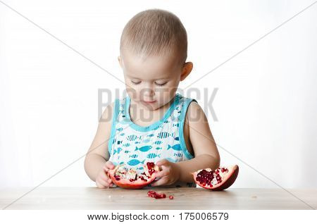 Baby eats a pomegranate ripe and juicy very tasty and joyfully