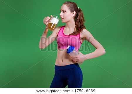 Caucasian girl that chooses between mug of beer or protein shake bottle. Choice concept.
