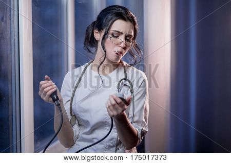 Brunette sassy female nurse in uniform smoking a cigarette measures the blood pressure