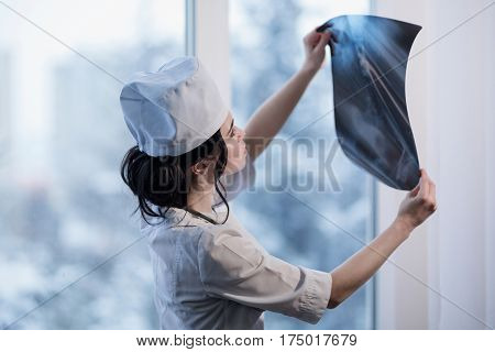 Caucasian woman looking at x-ray picture of backbone