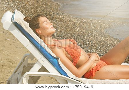 Beautiful woman is lying on the sunbed and enjoying of her vacation at the beach